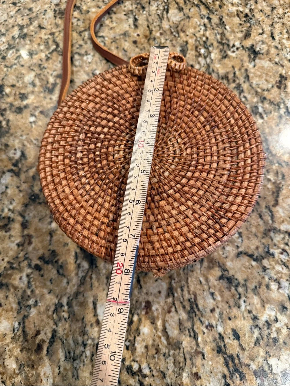 Tan, round, handwoven rattan crossbody bag